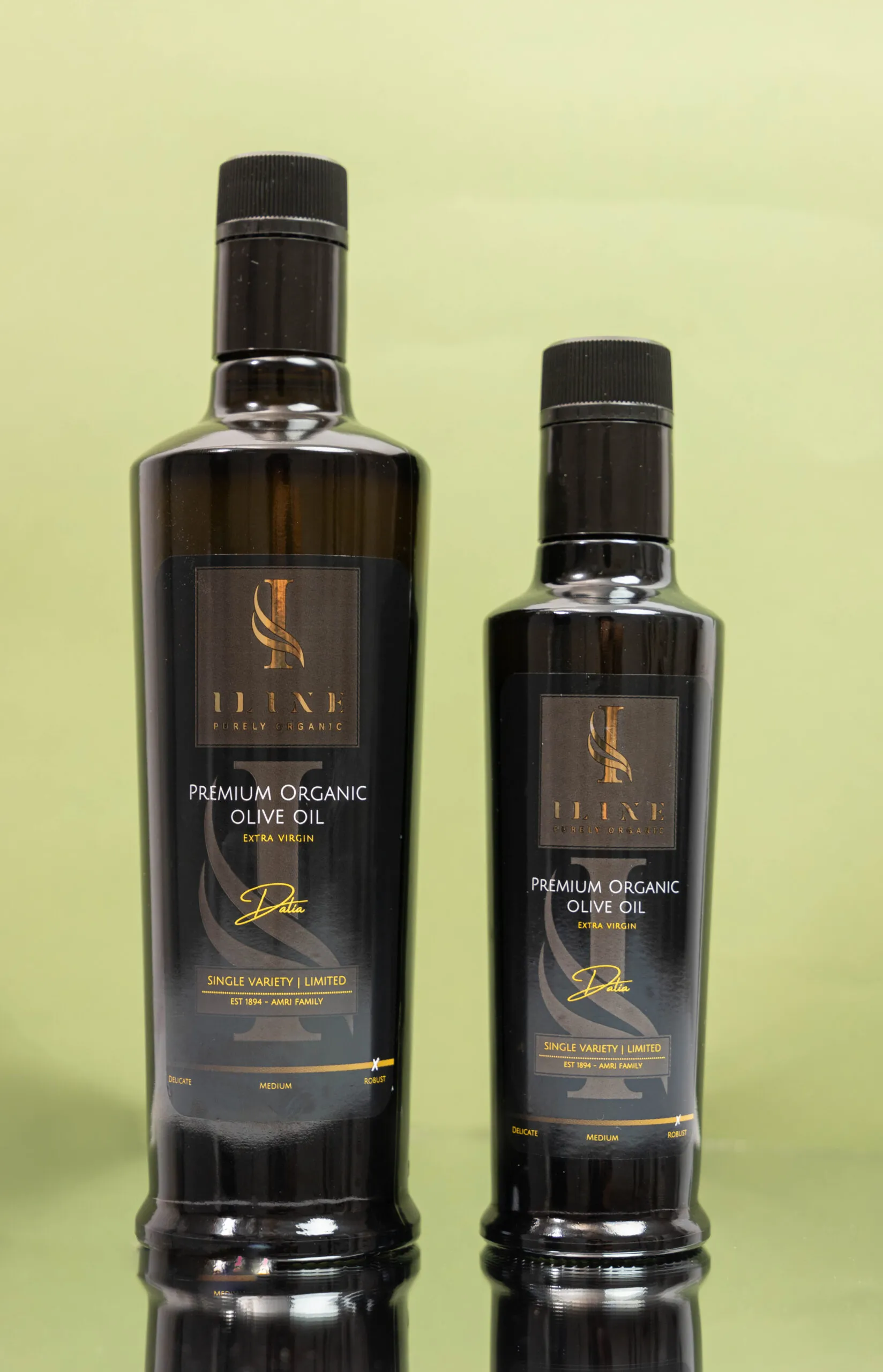 Zwei Flaschen Iline Organic Dalia Robust Bio-Olivenöl mit 250 ml und 500 ml Inhalt nebeneinander vor grünem Hintergrund.
