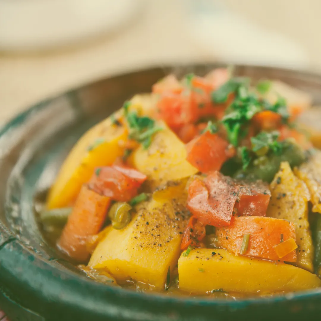 Kartoffelgericht mit Tomatenwürfeln, Kräutern und Gewürzen in einer traditionellen Tonschale